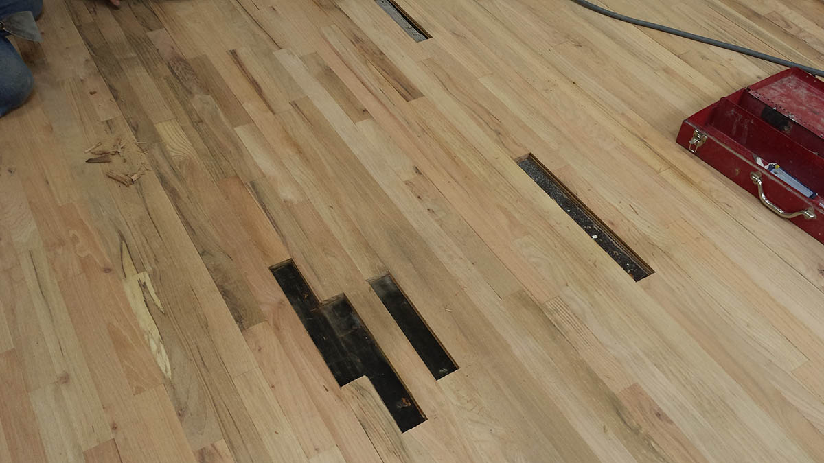 Oak hardwood floor with damaged boards removed for repair in Highland Park, IL by Midwest Hardwood Floors
