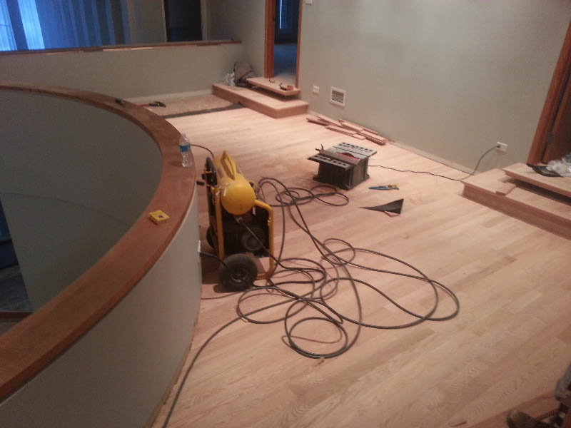 Red oak hardwood flooring installation in progress around a curved staircase in Chicago, IL by Midwest Hardwood Floors