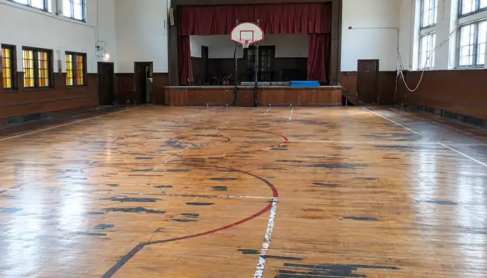 Worn gym hardwood floor before refinishing in Chicago, IL by Midwest Hardwood Floors